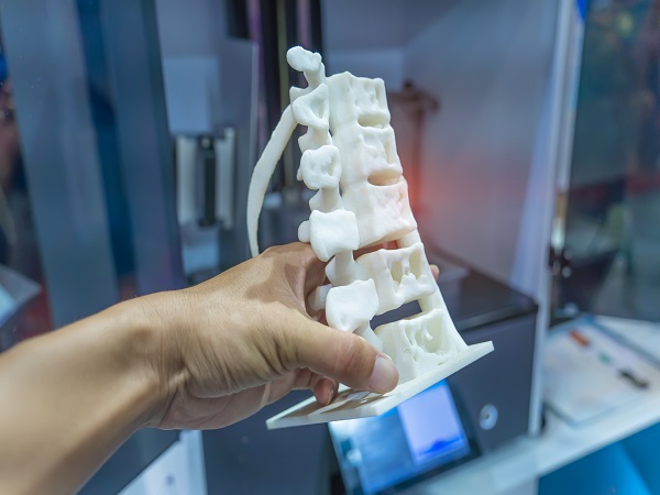hand with 3d printed human spine in 3d printer.