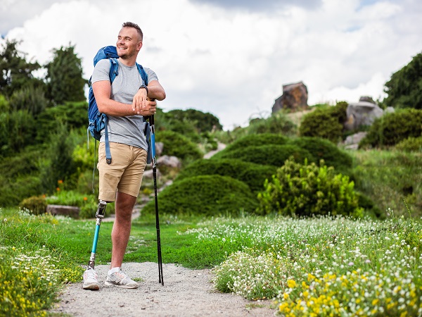 Cheerful man with prosthesis standing with Nordic walking sticks