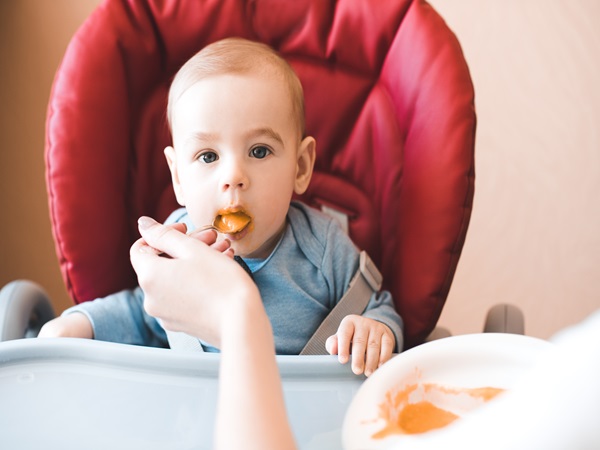 Baby boy eating in chair