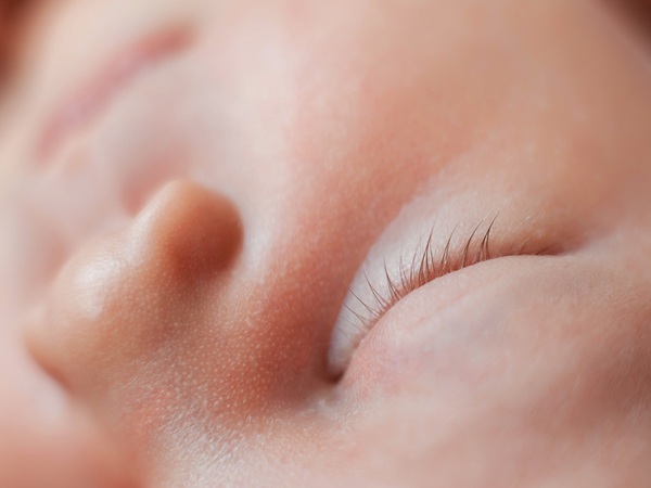 Close-up photo of closed eye of sleeping newborn baby girl.